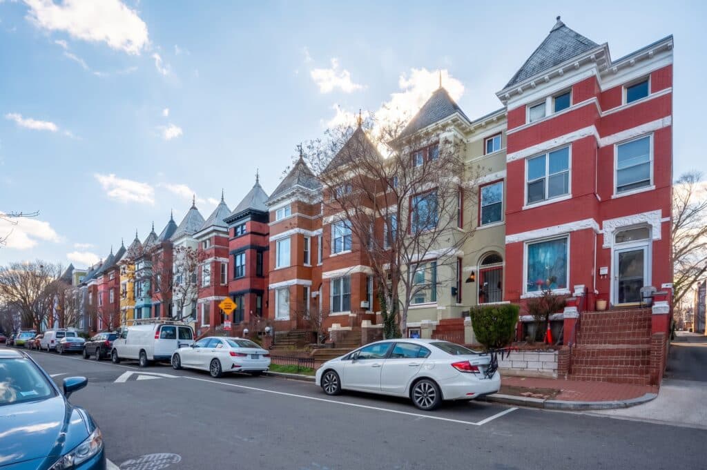 Victorian rowhouses with turrets along a street with parked cars
